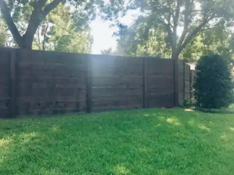 Dark-stained cedar privacy fence closes in a grassy backyard.
