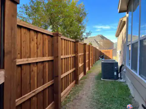 Black metal gate and cedar privacy fence secure a side drive.