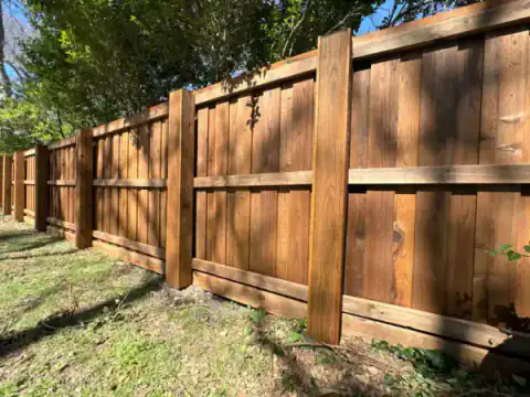 Cedar privacy fence screens the side of a brick home.