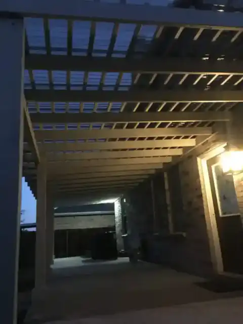 Covered patio structure takes shape beside a brick home.