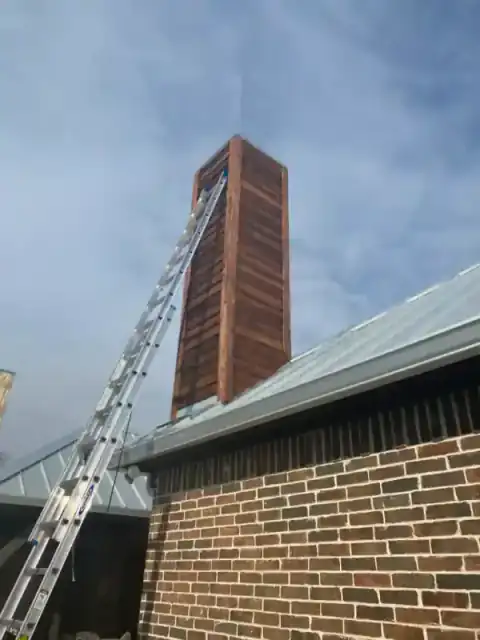 Masonry chimney rises beside a North Texas roof during construction.