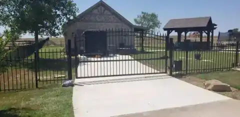 Black metal driveway gate meets a cedar privacy fence.