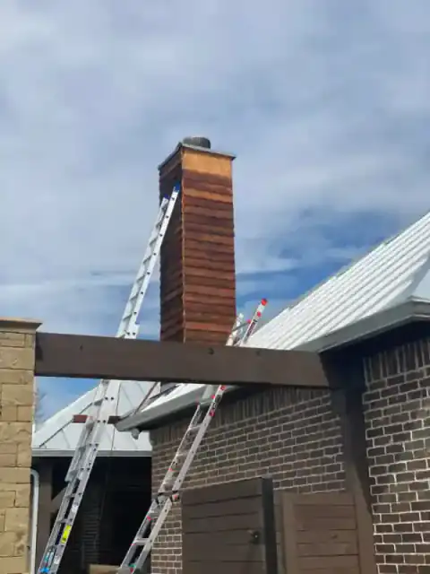 Brick chimney construction in progress beside a North Texas home.