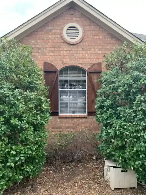 Brick home exterior framed by mature landscaping.