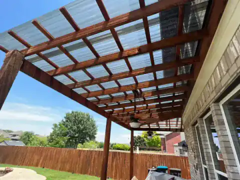 Cedar pergola roof covers a brick home's outdoor sitting area.