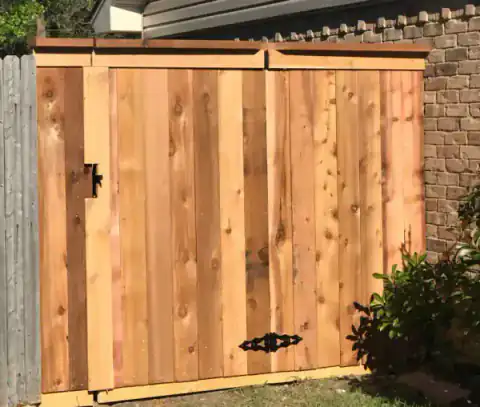 Cedar gate with black strap hinges closes a side passage.