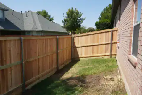 Cedar privacy fence encloses a residential backyard corner.