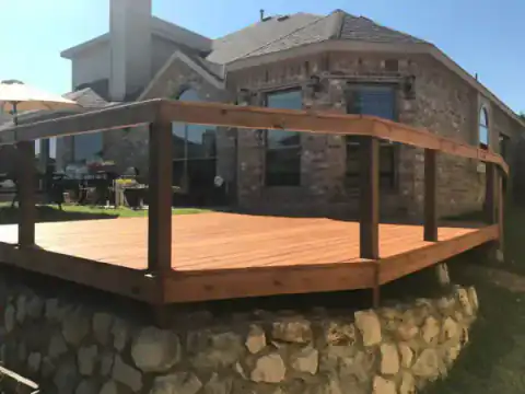 Raised cedar deck with railing overlooks a residential yard.