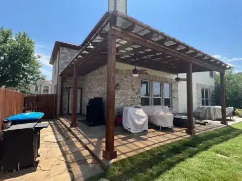 Cedar pergola covers a brick home's backyard patio.