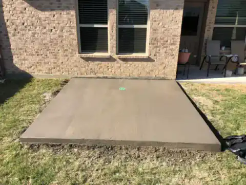 New concrete patio slab extends from a stone-faced home.