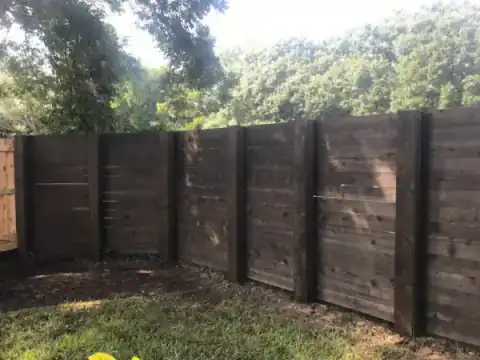Dark-stained cedar privacy fence spans a backyard.