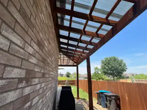 Cedar pergola attaches to a brick home over an outdoor patio.