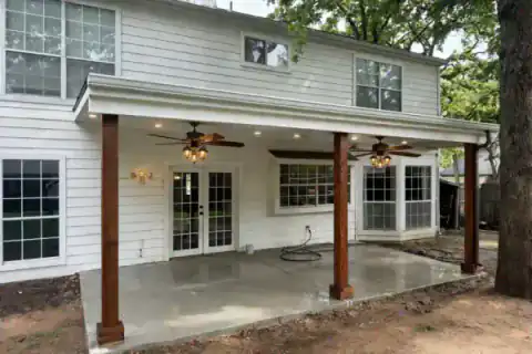 Covered patio addition spans the rear of a white-sided home.