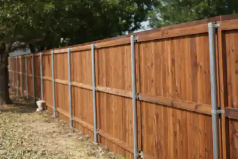 Cedar fence with galvanized support rails borders a backyard.