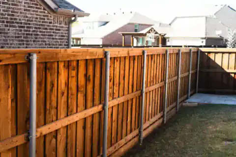 Cedar privacy fence borders a brick home's side yard.