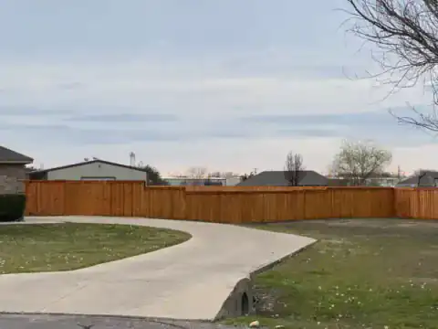 Cedar fence follows a curved residential street.