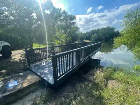 Black-railed footbridge crosses a pond beside a backyard.