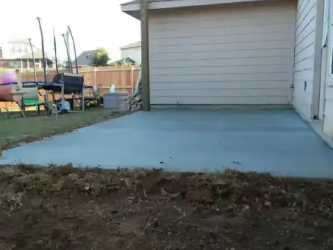 New concrete patio slab extends from a white-sided home.