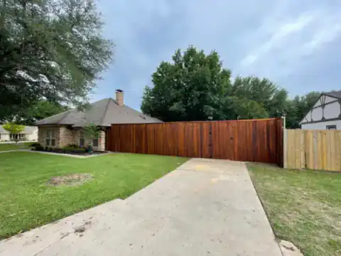 Cedar privacy fence borders a wide residential driveway.