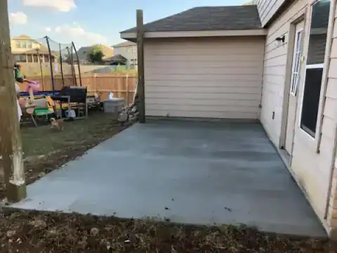 New concrete patio pad sits beside a residential garage.
