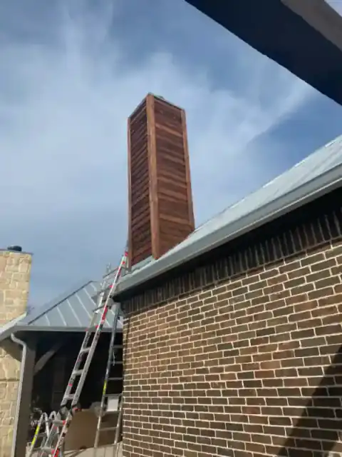 Brick chimney construction in progress beside a North Texas home.