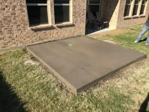 New concrete patio slab extends from a stone-faced home.