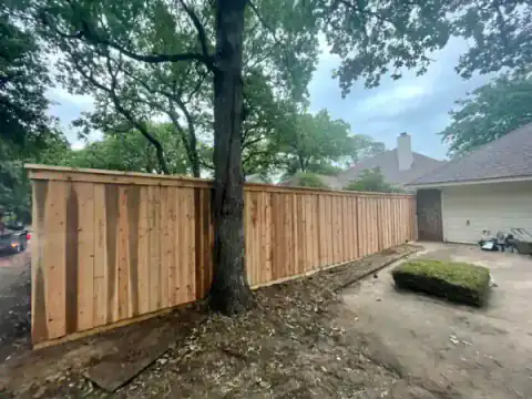 Cedar fence follows a mature tree line behind a home.