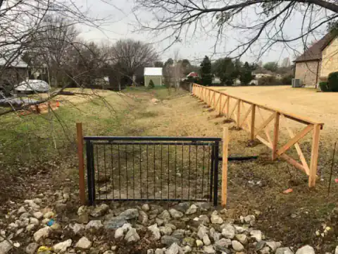 Horizontal rail fence borders an open North Texas property.