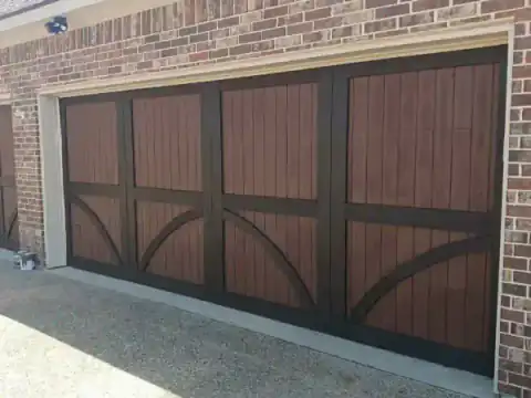 Brown carriage-style garage doors set into a brick facade.