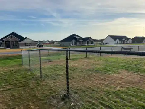 Black metal fence encloses an open residential property.