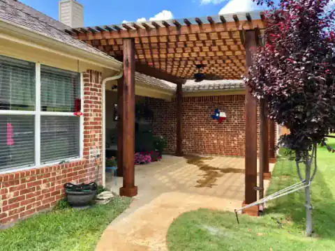 Cedar pergola shades a brick home's outdoor living area.