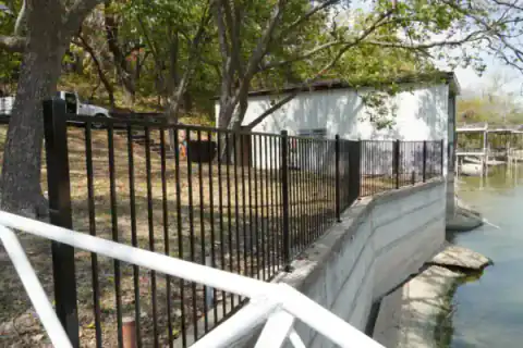 Black metal fence borders a concrete water channel.