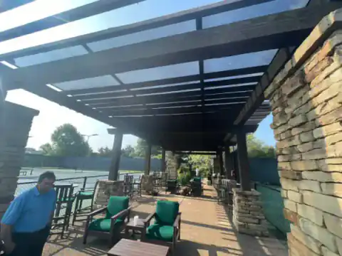 Stone-column pergola shelters an outdoor living space.